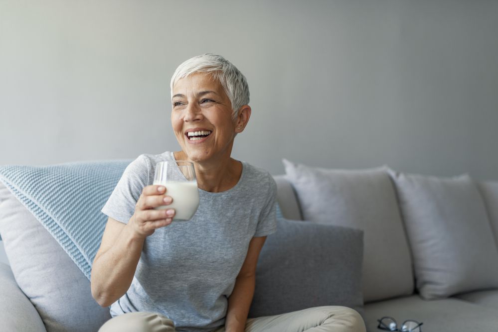 Donna anziana beve un bicchiere di latte