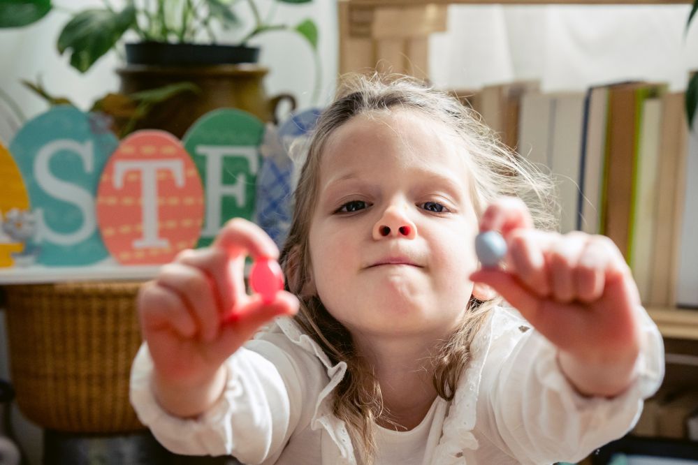 Bambina di 3 anni con una caramella in ciascuna mano