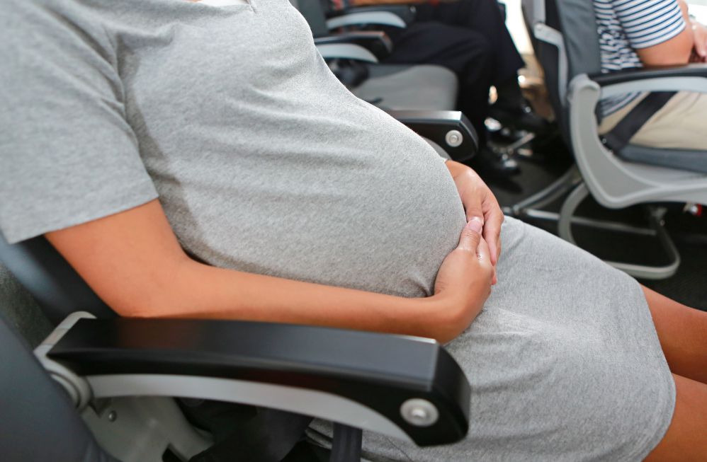 Donna in gravidanza seduta su una poltrona di aereo