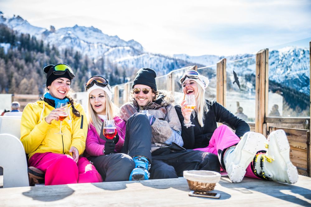 Gruppo di persone in abito da sci bevono alcol sulla neve